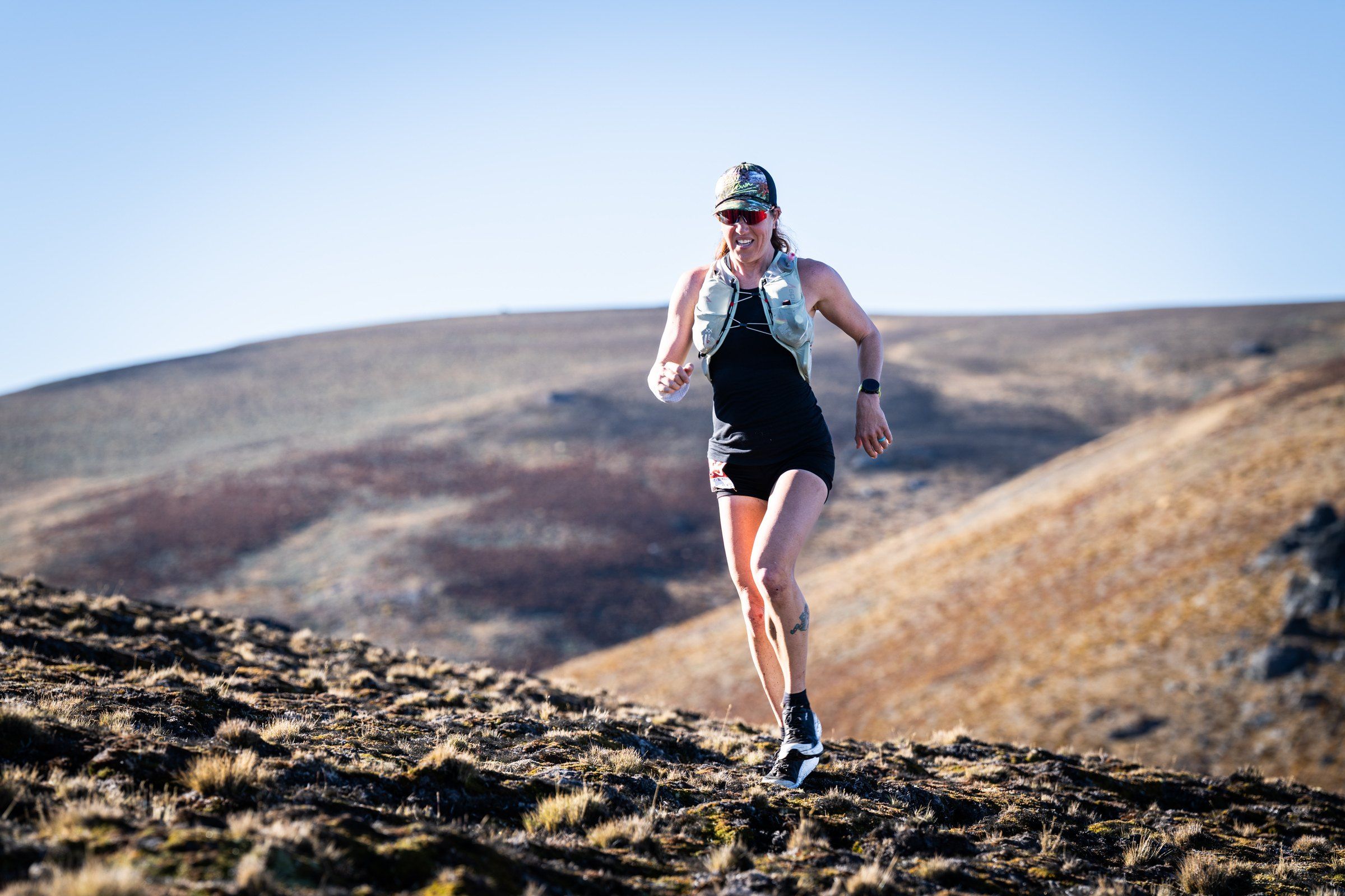 Megan Eckert running along a high ridge in the Otago hills, New Zealand, at the Northburn 100 in March 2026