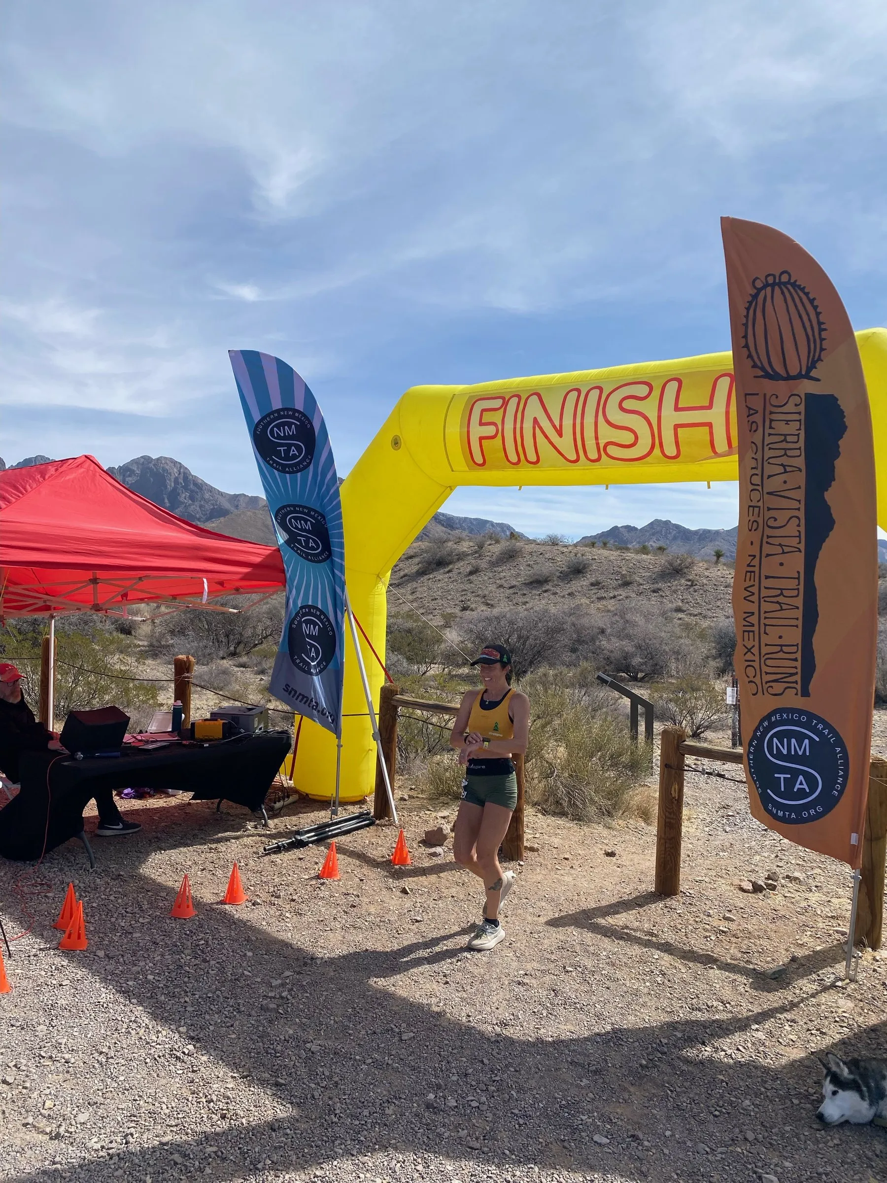 Megan Eckert standing at the finish arch of the Sierra Vista Trail Runs