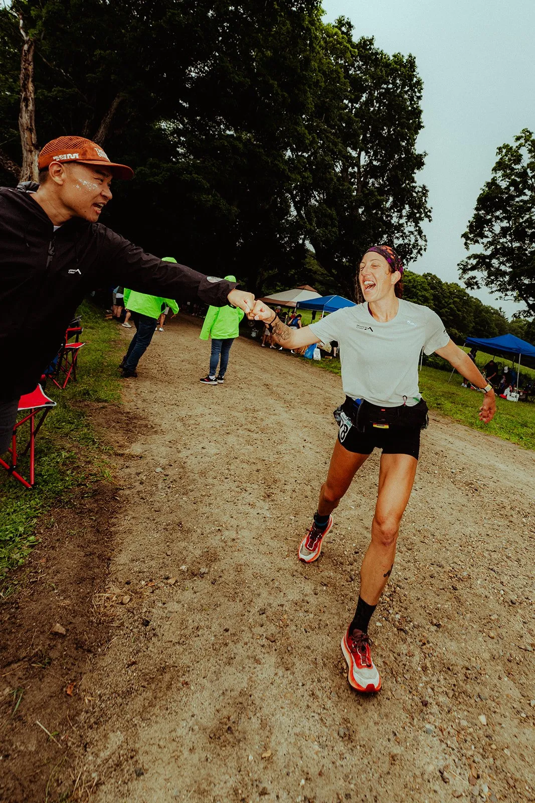 Megan Eckert high-fiving a spectator on a dirt road at the Vermont 100